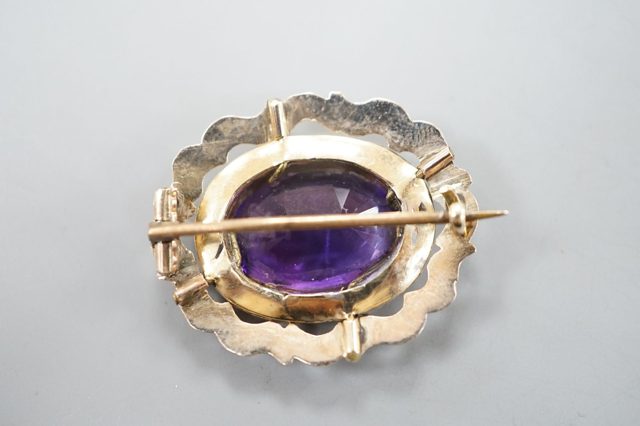 A yellow metal and amethyst set brooch, 29mm, gross 5.7 grams.